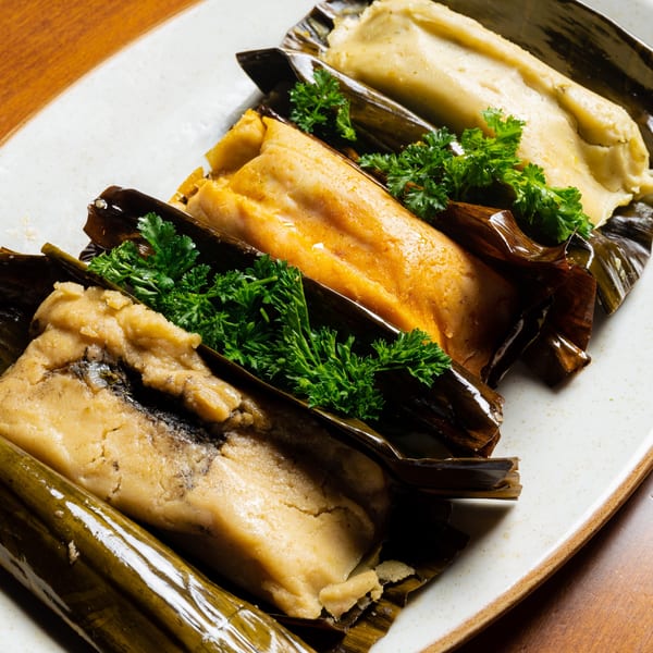 A plate of three Picos Restaurant tamales, two yellow and one dark, garnished with parsley.