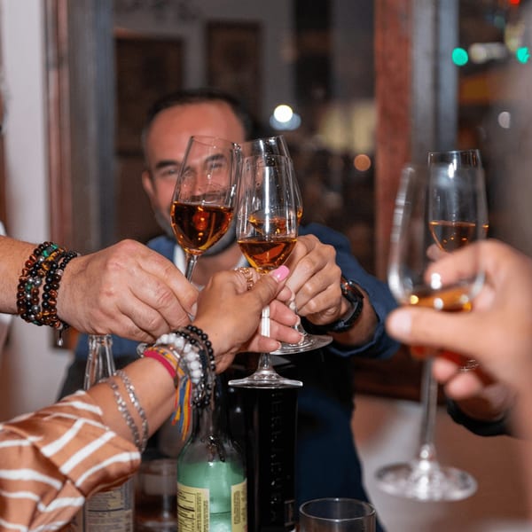 Friends toasting with amber drinks in wine glasses at Picos Restaurant, celebrating a special occasion.