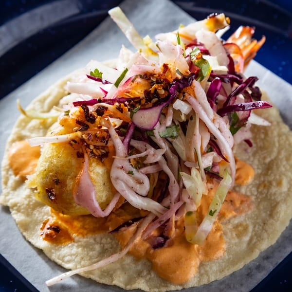 Close-up of a Picos Restaurant shrimp taco with slaw and orange sauce on a blue plate.